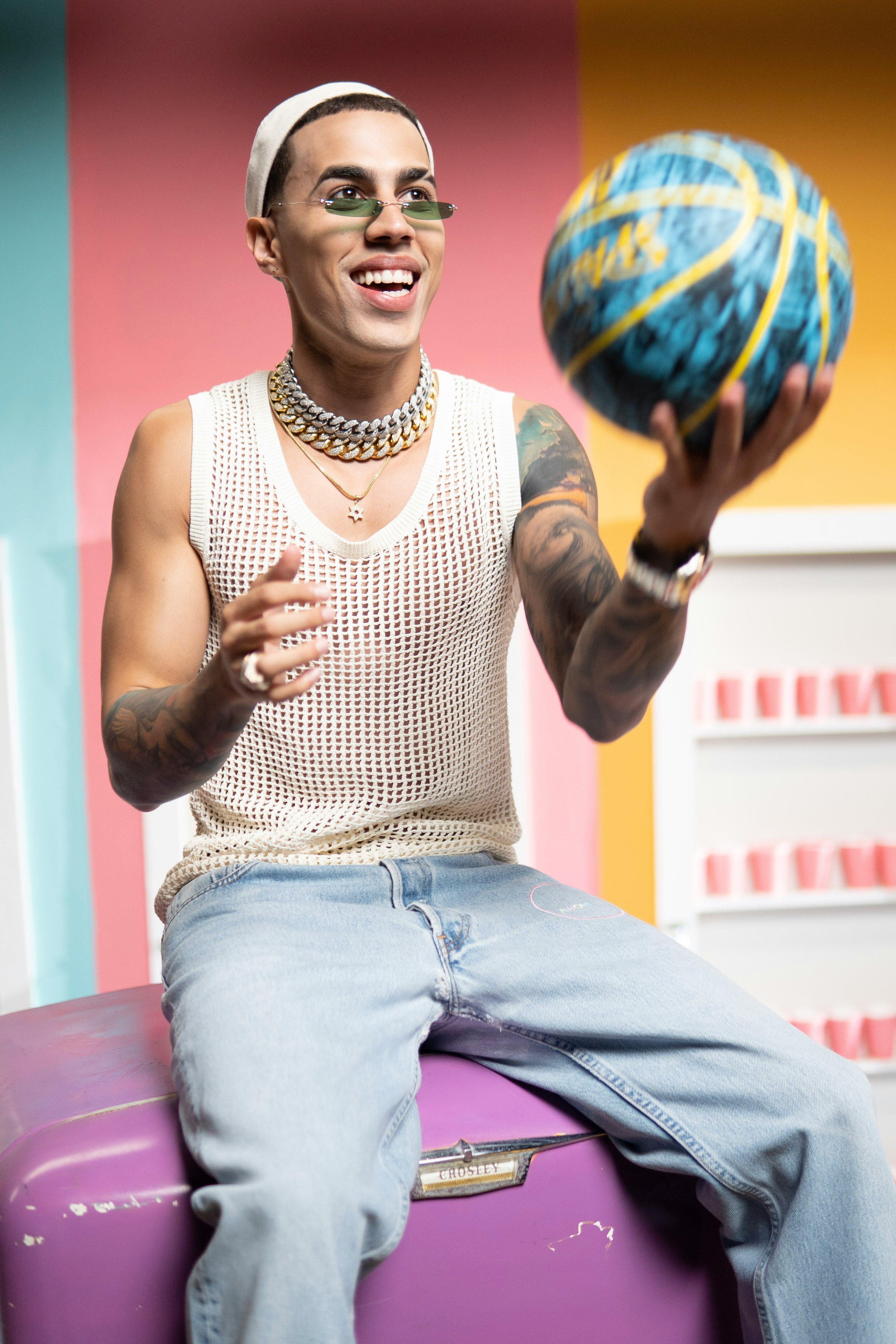 man in white and black polka dot tank top and blue denim jeans holding red and